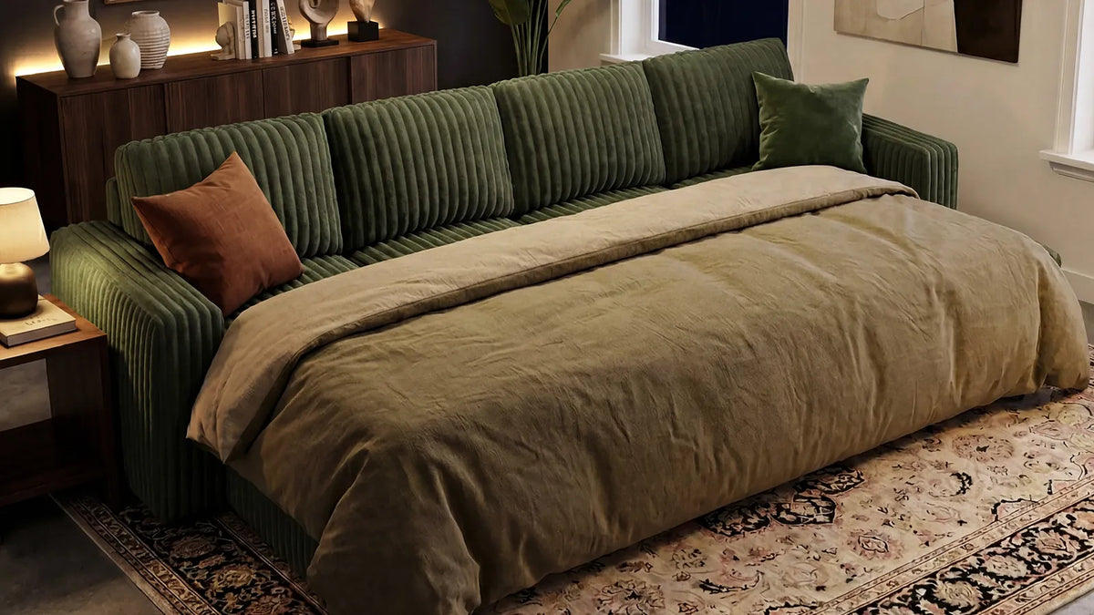 Gray pull-out sectional sofa in a living room with a chaise, round wooden coffee table, fireplace, patterned rug, and decorative pillows