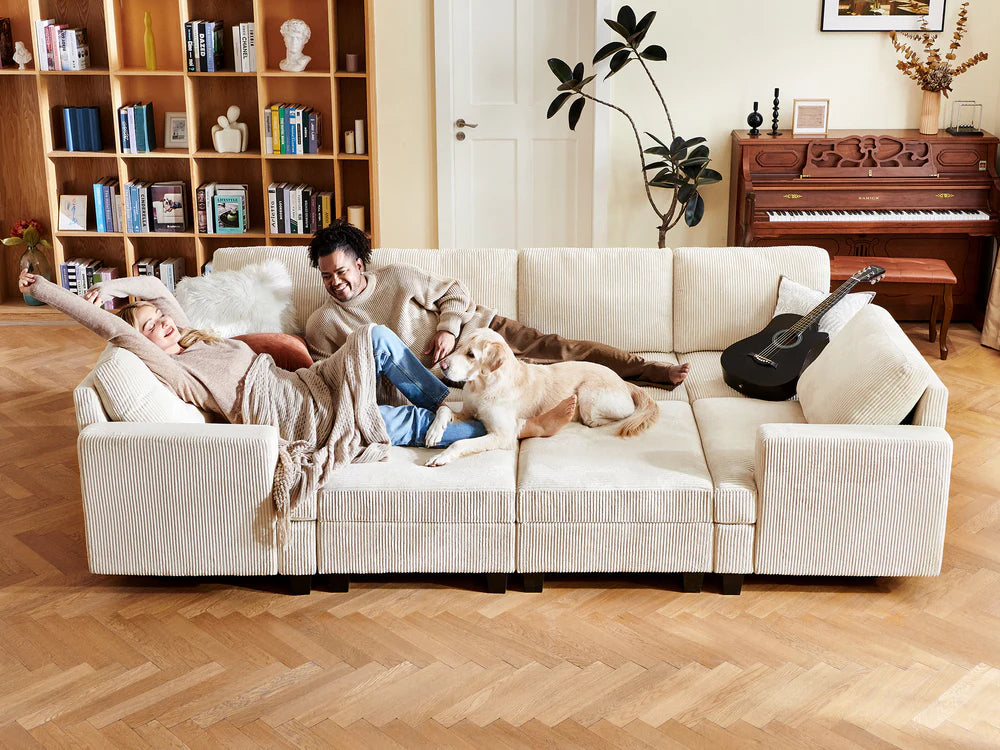 a couple and their dog lounging on a corduroy sofa