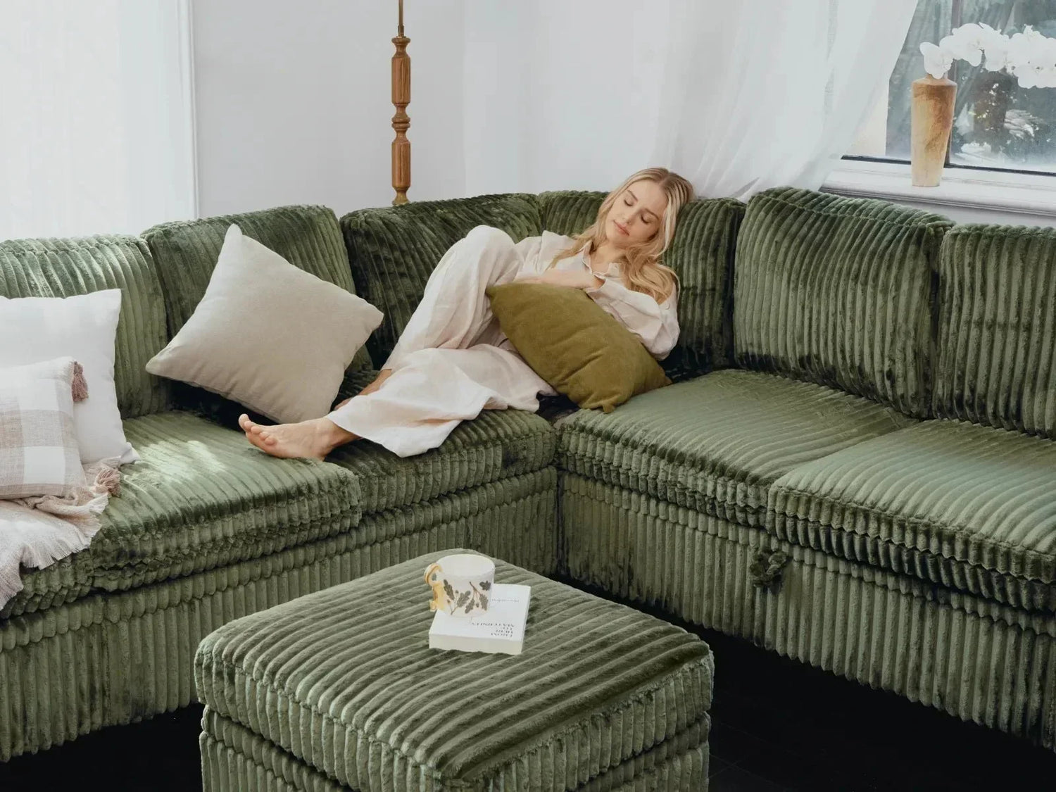 Relaxed woman resting on plush green ribbed fabric modular couch