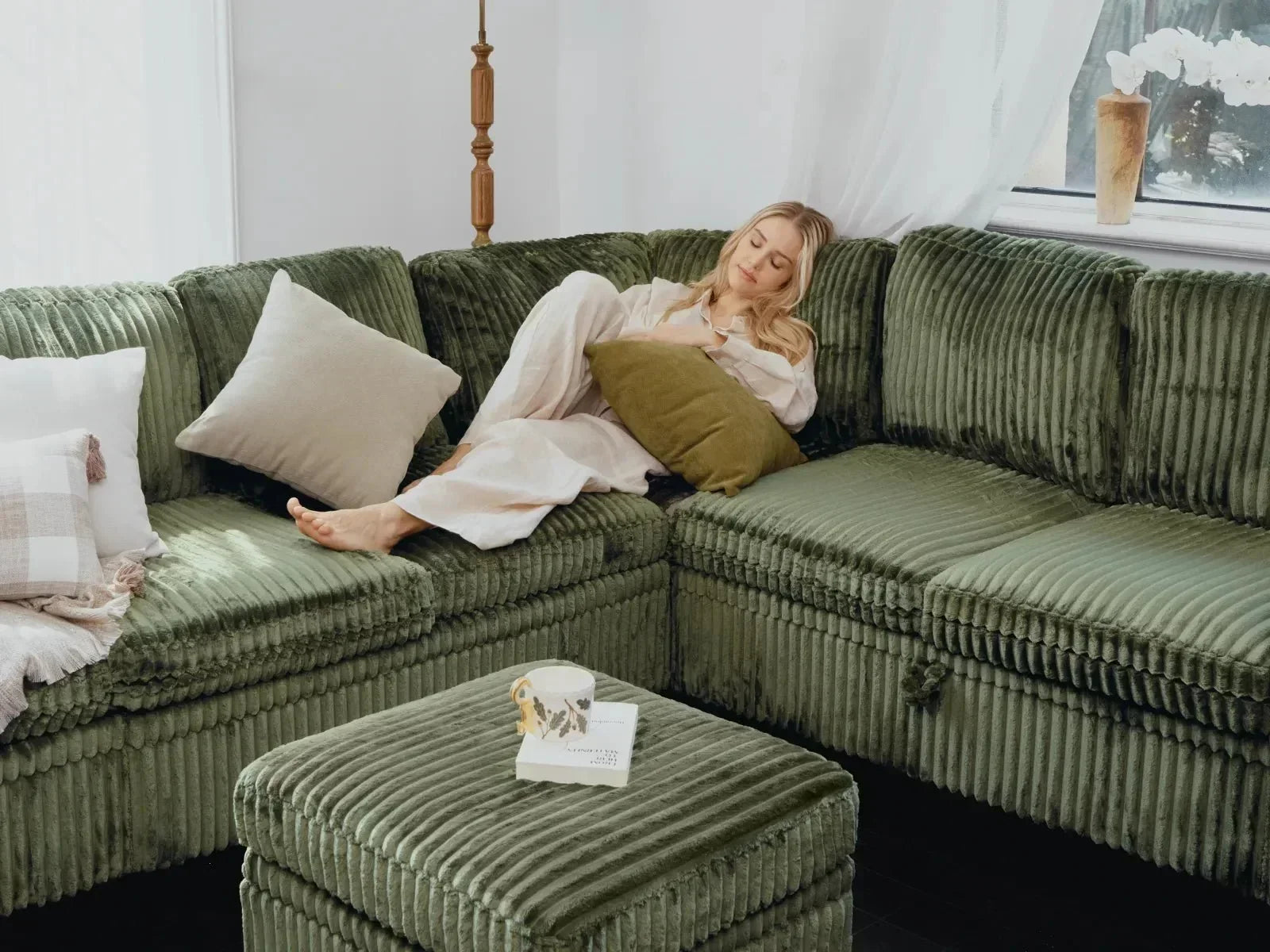 Relaxed woman resting on plush green ribbed fabric modular couch